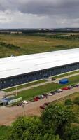 Exterior of newly built factory. View from the air on a modern manufacturing construction in the countryside in summer. Aerial view. Motion camera forward. Vertical video