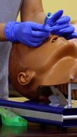 Medic shows how to insert oxygen tube in nose of a medical dummy. Competent doctor with nesessary instruments in hands. Vertical video