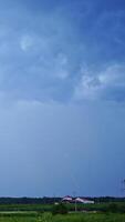 Set of beautiful lightning strikes on blue background. Small electrical lightnings in the sky over the green nature in the evening. Vertical video