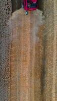 Heavy technics in wheat field. Red combine harvesting dry wheat. Observing process. View from above. Vertical video