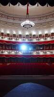 Selective focus from stage on empty rows with red velvet seats in theater hall. Rows with empty chairs. No people because of covid-19. Vertical video