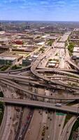 Road loops and junctions with multiple automobiles moving along. Low architecture of Chicago city. Aerial view. Vertical video