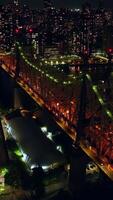 Tremendous Queensboro Bridge in orange and green lights. Lively traffic in neversleeping New York. Cityscape with billions of lights at backdrop. Vertical video