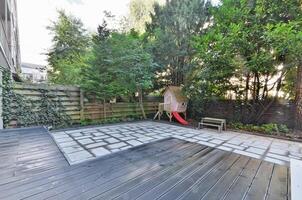 A backyard with a wooden deck and a swing set photo