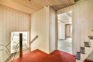 A hallway with a red carpet and wooden stairs photo