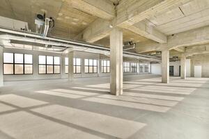 An empty warehouse with large windows and concrete floors photo