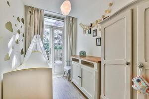 A small room with a crib, a dresser and a window photo