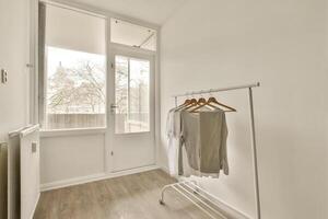 A white room with a clothes rack and a window photo