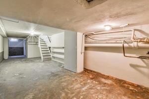 A basement with a staircase and a pipe photo