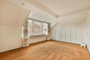 A large empty room with a window and a closet photo