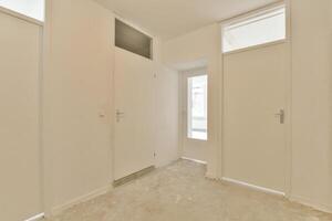 A white hallway with two doors and a window photo
