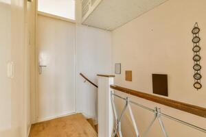 A narrow hallway with a wooden railing and a door photo