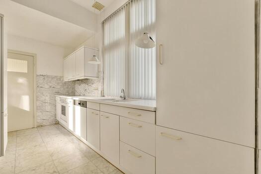 A kitchen with white cabinets and a window photo