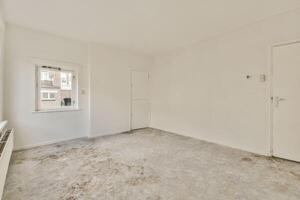 An empty room with a white door and a window photo