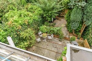 A view of a garden from above with a patio and table photo