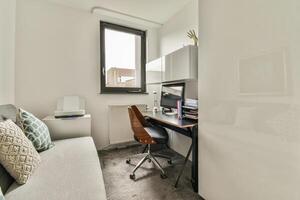 A small office with a desk, chair and window photo