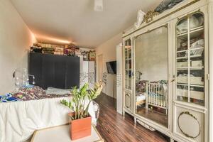 A small room with a bed, a cabinet and a mirror photo