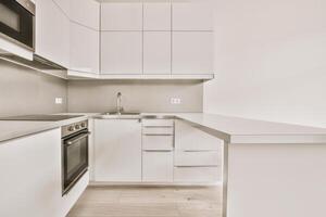 A white kitchen with a sink, stove, and microwave photo