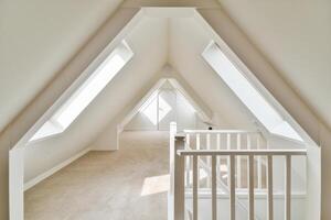A white attic with a staircase and a window photo