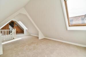 A large attic with a window and a carpeted floor photo