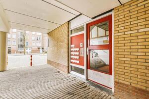 A brick building with a red door and a brick walkway photo