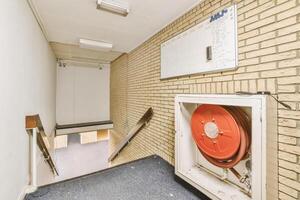 A hallway with a red fire hose and a wall photo