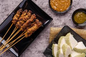 Pork Satay or Sate Babi. Pork Satay served with a Peanut sauce and slices of lontong or ketupat photo