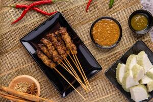 Pork Satay or Sate Babi. Pork Satay served with a Peanut sauce and slices of lontong or ketupat photo