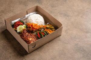 In Indonesian it is called Rice Box or Nasi kotak with ayam rendang. Usually distributed during celebrations or catering packaging. photo
