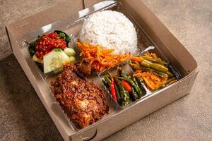 In Indonesian it is called Rice Box or Nasi kotak with ayam rendang. Usually distributed during celebrations or catering packaging. photo