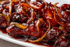 ayam goreng mentega or fried chicken with soy sauce, butter and onion served on white plate. photo
