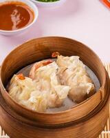 Assorted Chinese Dimsum in bamboo basket. Dimsum is a large range of small dishes that Cantonese people traditionally enjoy in restaurants for breakfast and lunch. photo