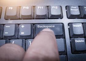 The finger push on the Backspace key on the keyboard, clear data computers concept. photo