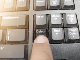 The finger push on the Delete key on the keyboard, clear data computer concept. photo