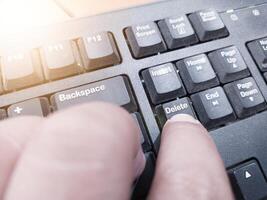 The finger push on the Delete key on the keyboard, clear data computer concept. photo