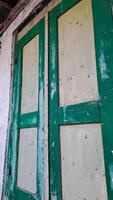 features a pair of aged wooden window shutters painted in green and white. The shutters are weathered and distressed photo