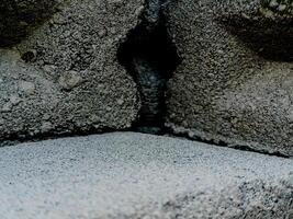 weathered concrete surface, showcasing the rough texture, cracks, and shadows created by its uneven surface. photo