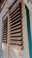 A pair of old, wooden window shutters painted in light beige with a teal frame. photo