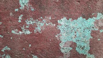 This weathered wall features peeling paint in shades of red and blue, creating a visually interesting and textured surface. photo