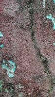 weathered wall with peeling paint in shades of blue, red, and white. The texture is rough and uneven, with visible cracks and chips photo