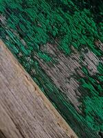 photo features a piece of wood with peeling teal paint. The texture is rough and aged