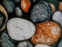 photo shows smooth, rounded stones arranged in a mosaic. The stones vary in color and texture.