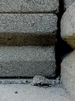 weathered concrete surface, showcasing the rough texture, cracks, and shadows created by its uneven surface. photo