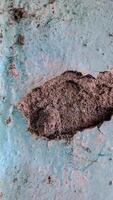 cracked and weathered wall surface. The paint is peeling and the concrete is exposed, creating a textured and distressed look photo