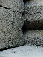 weathered concrete surface, showcasing the rough texture, cracks, and shadows created by its uneven surface. photo