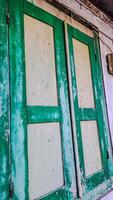 features a pair of aged wooden window shutters painted in green and white. The shutters are weathered and distressed photo