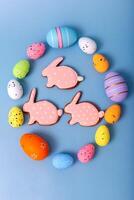 Three gingerbread in the form of a rabbit inside an oval frame of multicolored Easter eggs photo
