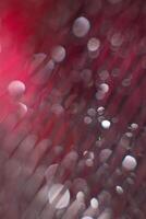 glare from water on a black mesh on a blurred red background. Abstract background photo