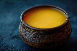 Golden liquid in an ornate bowl on a dark surface photo