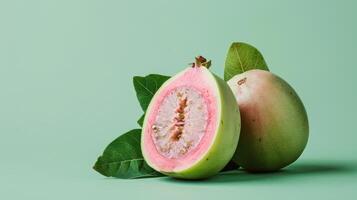 A Single Slice of Pink Guava With A Whole Guava and Green Leaves on a Light Green Background photo